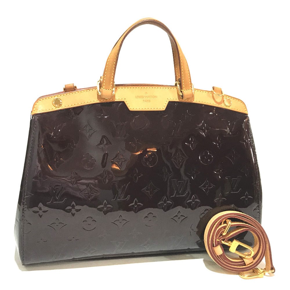 Black handbag with gold accents and monogram pattern on a white background