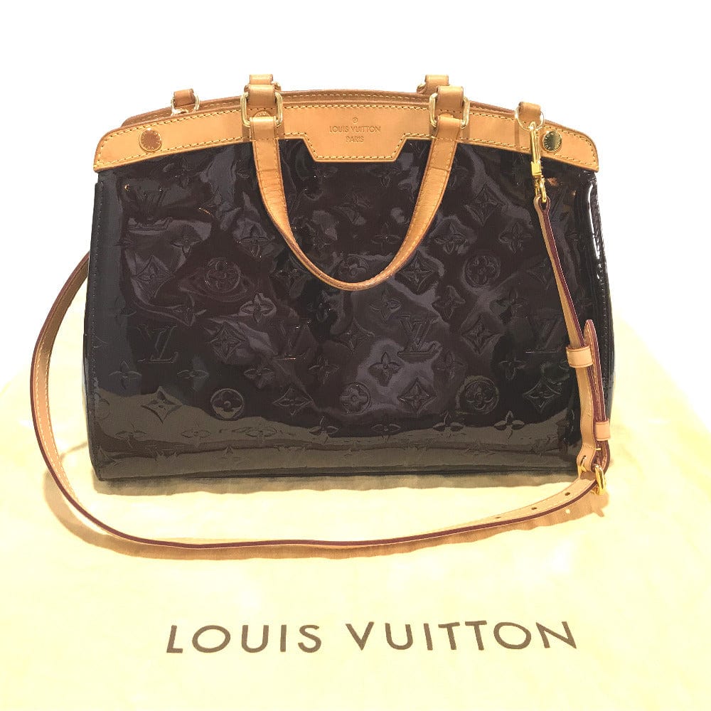 Louis Vuitton handbag with black monogram pattern and gold accents on a white background