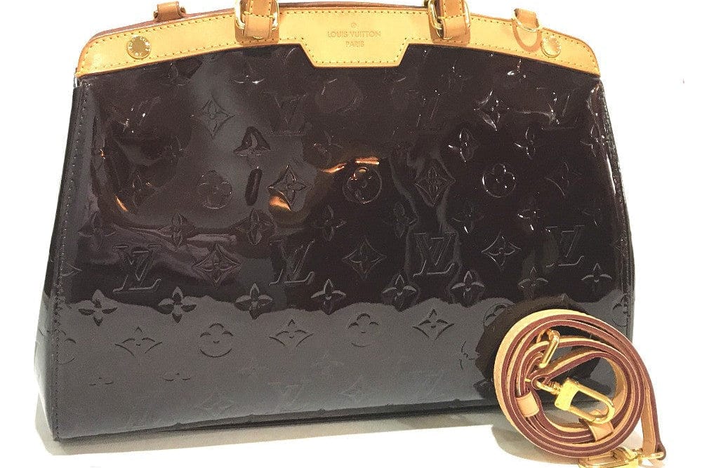 Black handbag with gold accents and monogram pattern on a white background