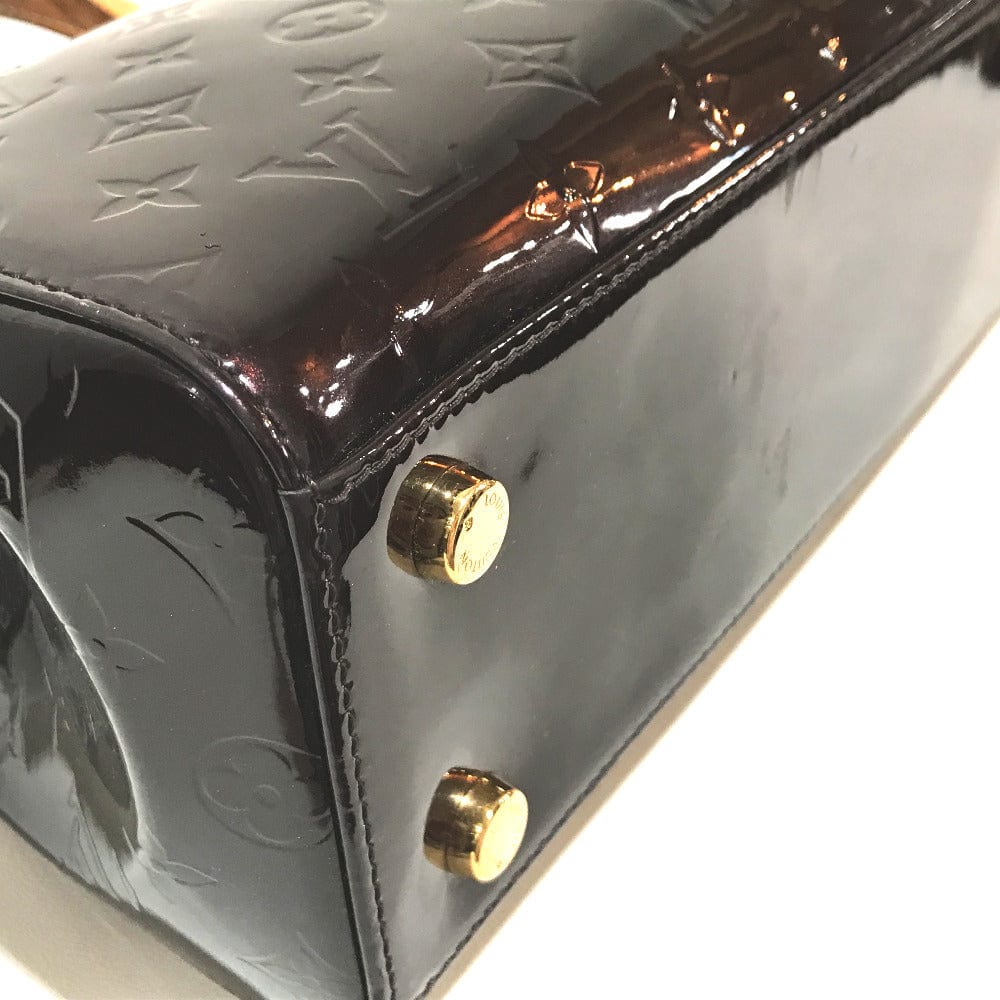 Shiny black handbag with gold studs on a white background