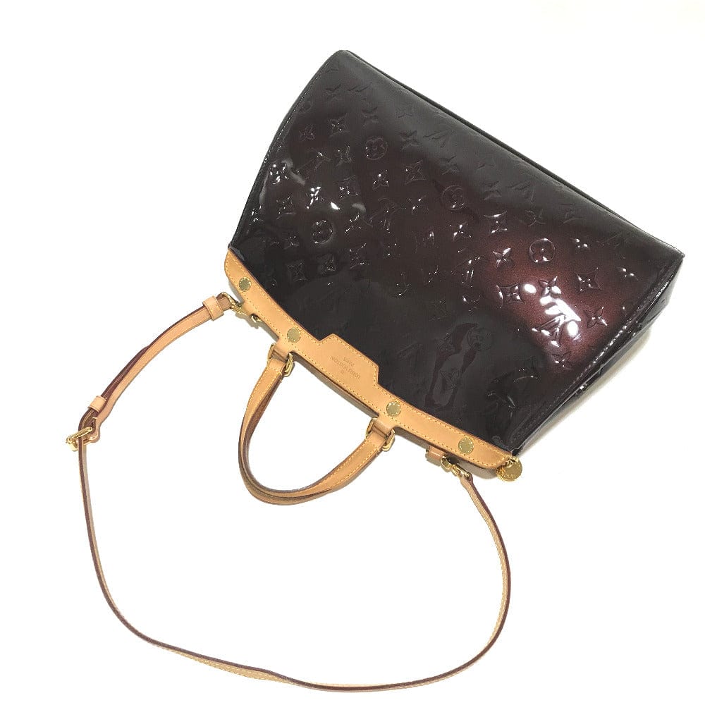 Brown leather handbag with gold handle and strap on a white background