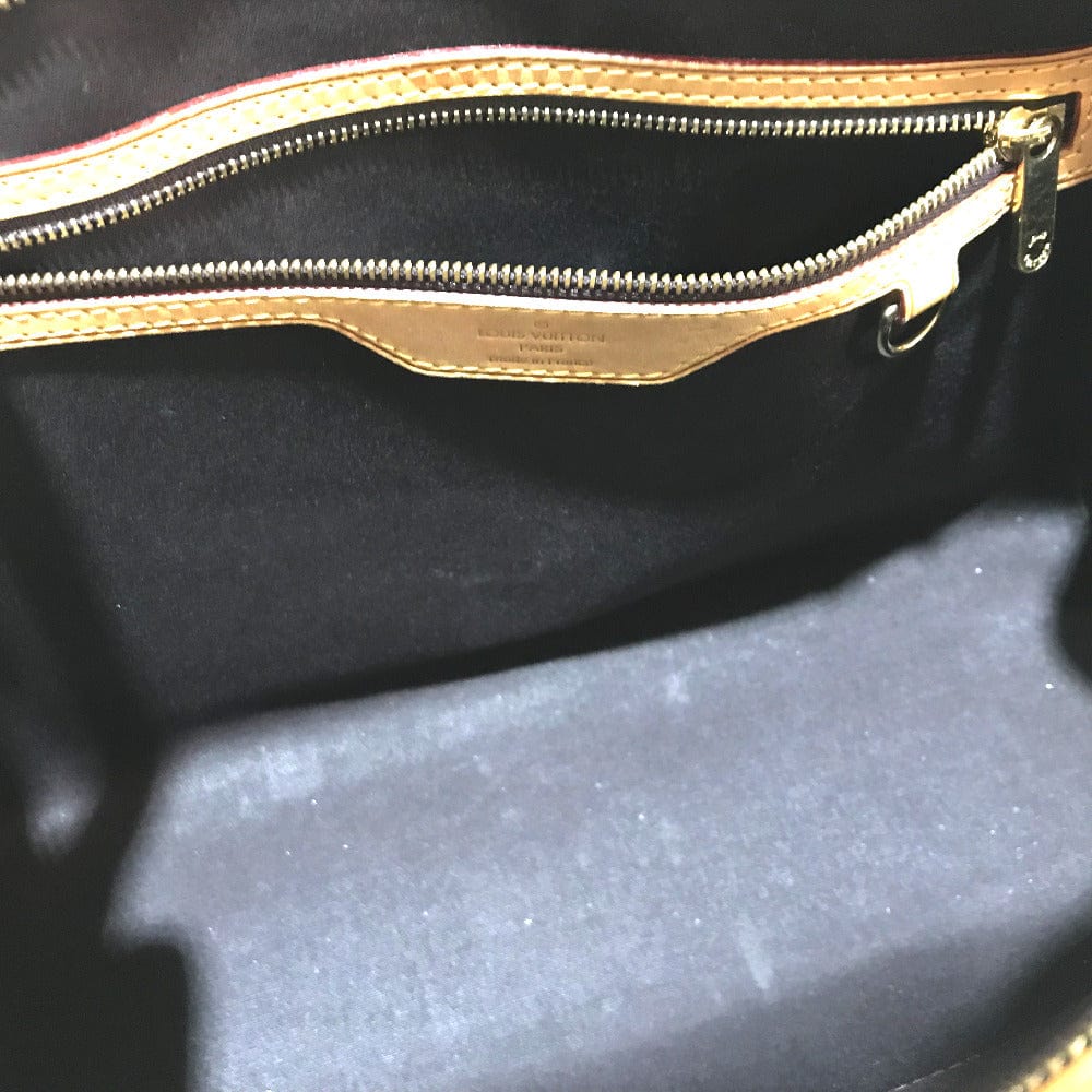 Close-up of a black bag with a gold zipper, featuring the brand name.