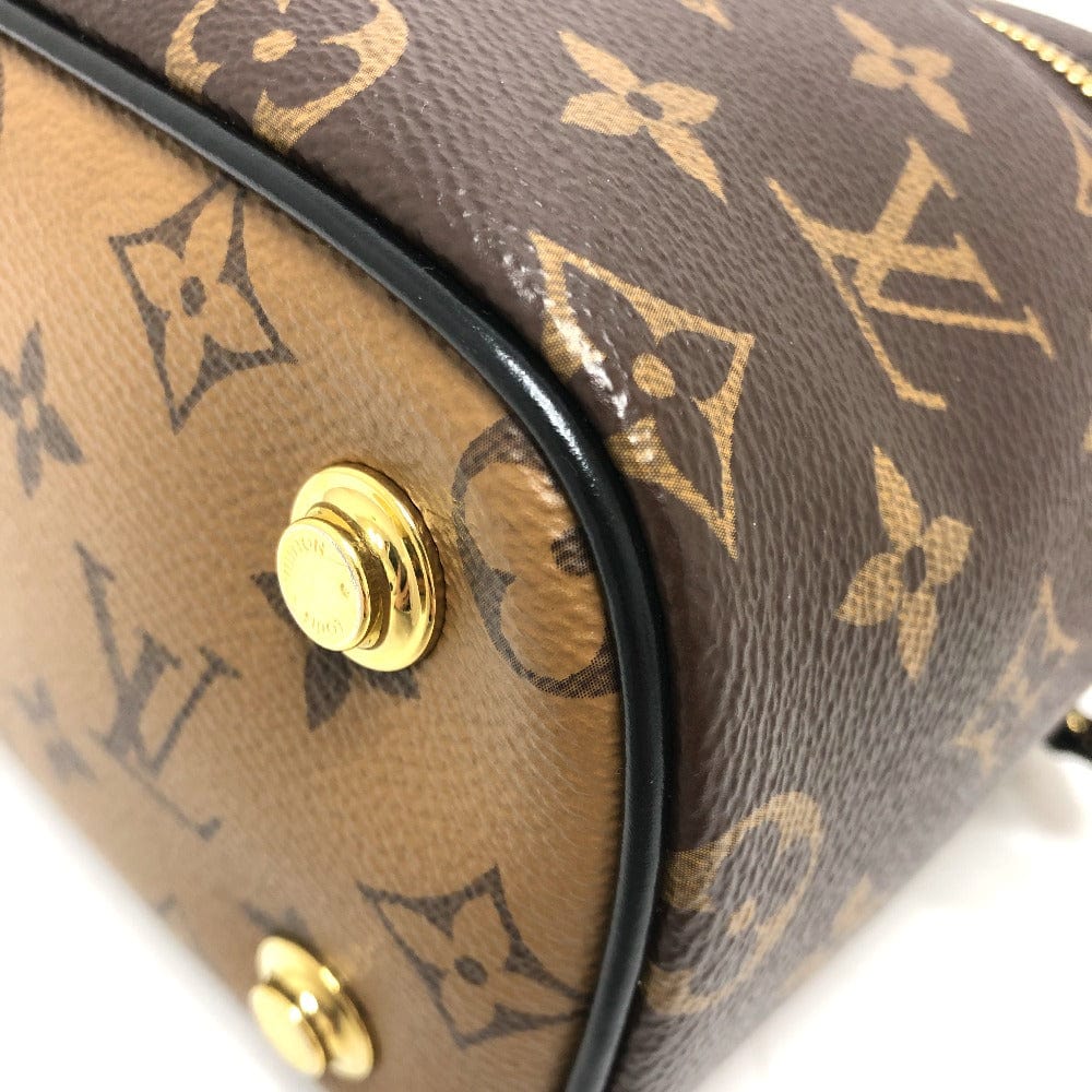 Close-up of a brown handbag with gold monogram pattern and gold buttons.