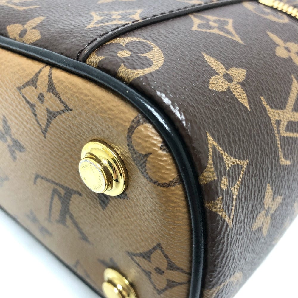 Close-up of a brown leather handbag with gold accents and monogram pattern.