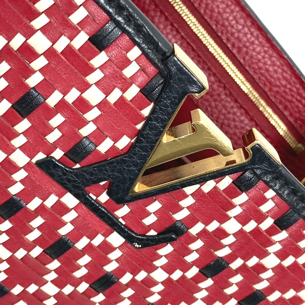 Close-up of a red and black patterned handbag with gold and black hardware.