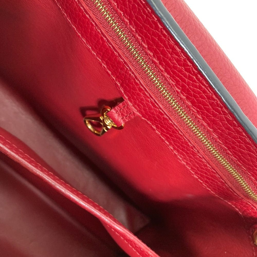 Close-up of a red leather handbag with a gold zipper pull.