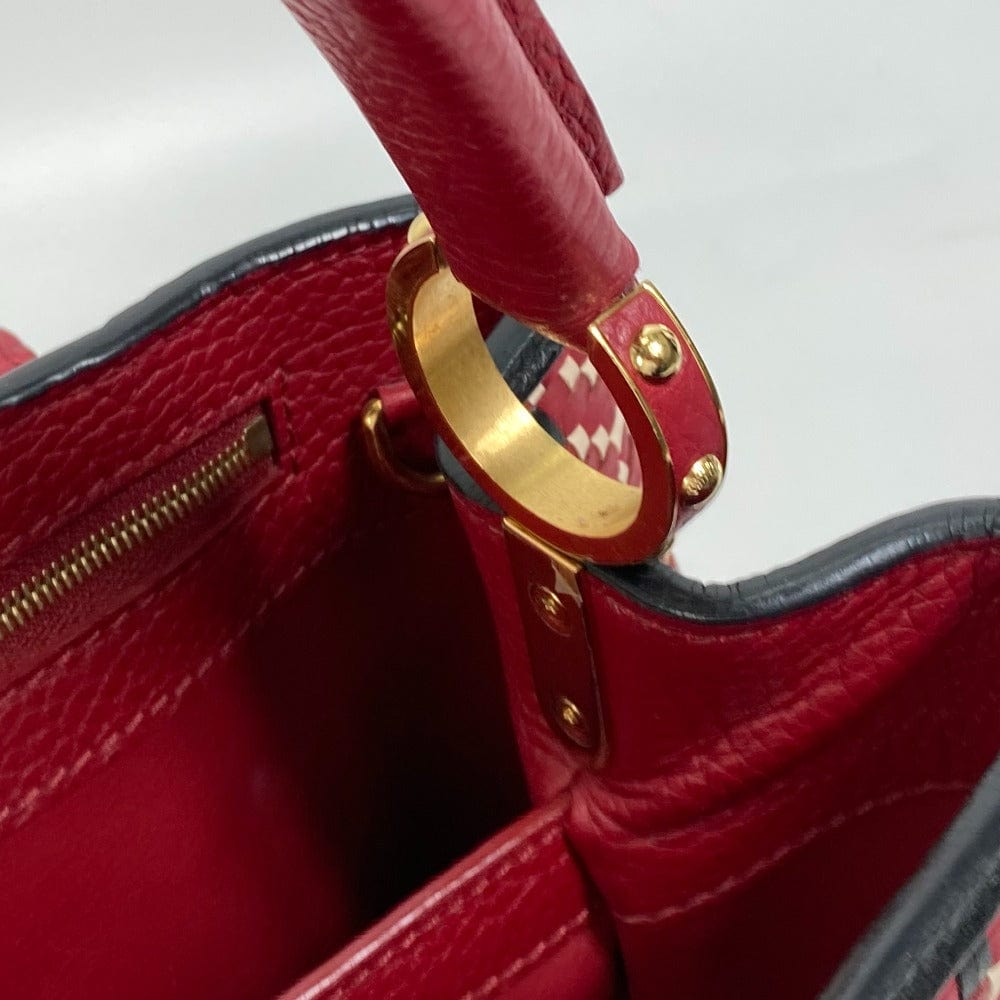 Close-up of a red handbag with gold handle and clasp on a white background
