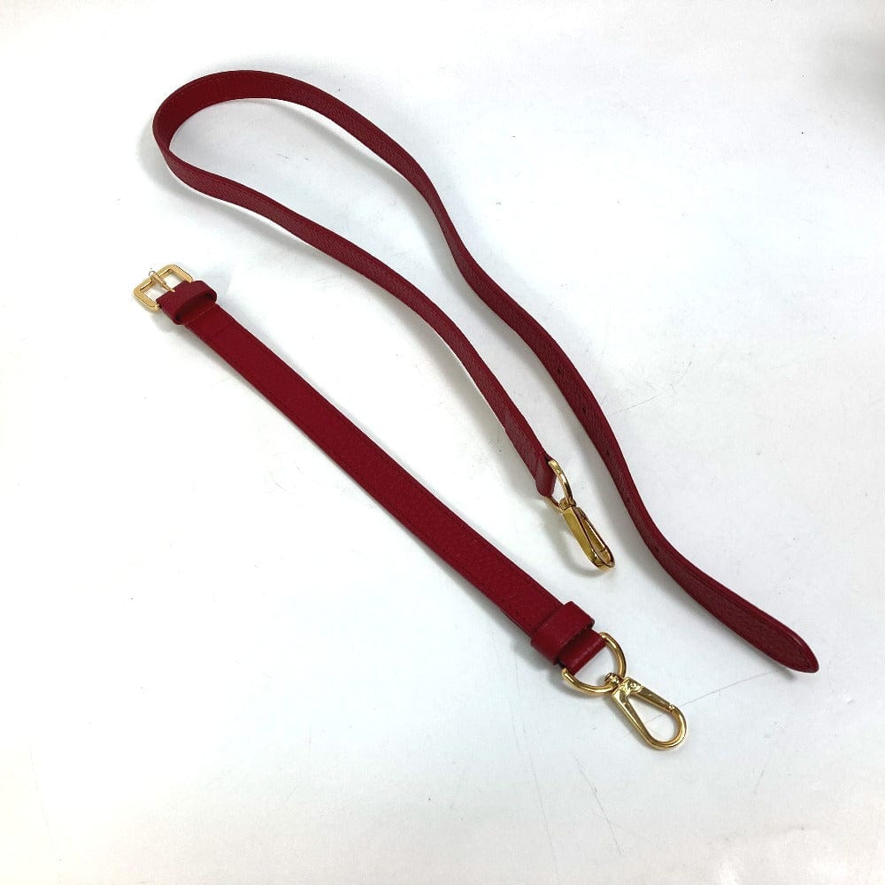 Red leather strap with gold hardware on a white background