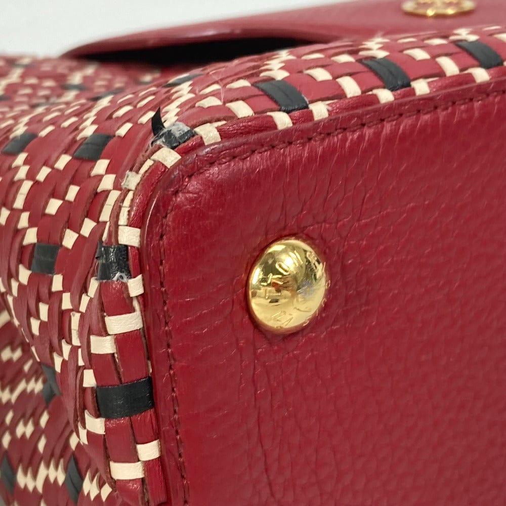 Close-up of a red handbag with woven pattern and gold button detail.