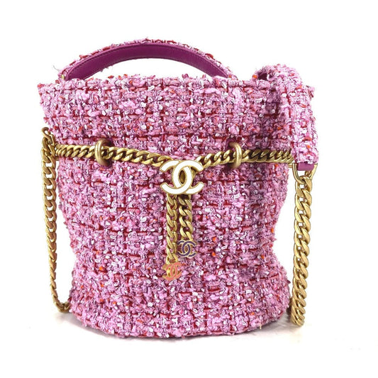 Pink tweed handbag with gold chain and Chanel logo on a white background