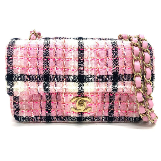 Pink and black checkered handbag with gold chain on a white background