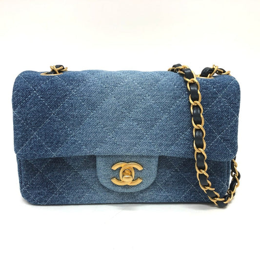 Blue denim handbag with gold chain and clasp on a white background
