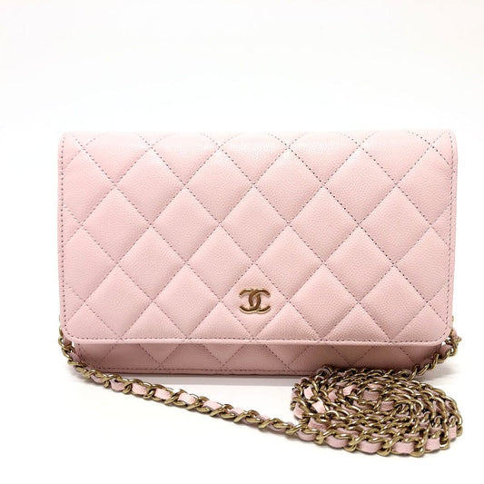 Pink quilted handbag with gold chain strap on a white background