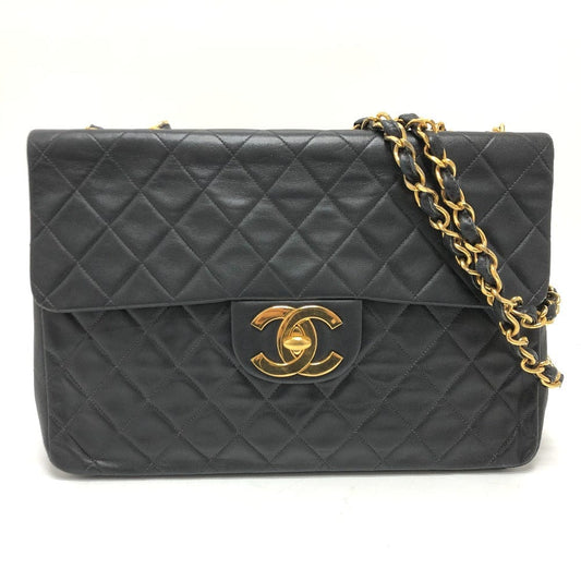 Black quilted handbag with gold chain strap and logo on a white background