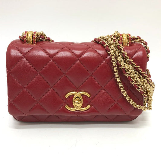 Red quilted handbag with gold chain and clasp on a white background