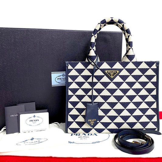 Prada handbag with geometric pattern, belt, and packaging on a white background