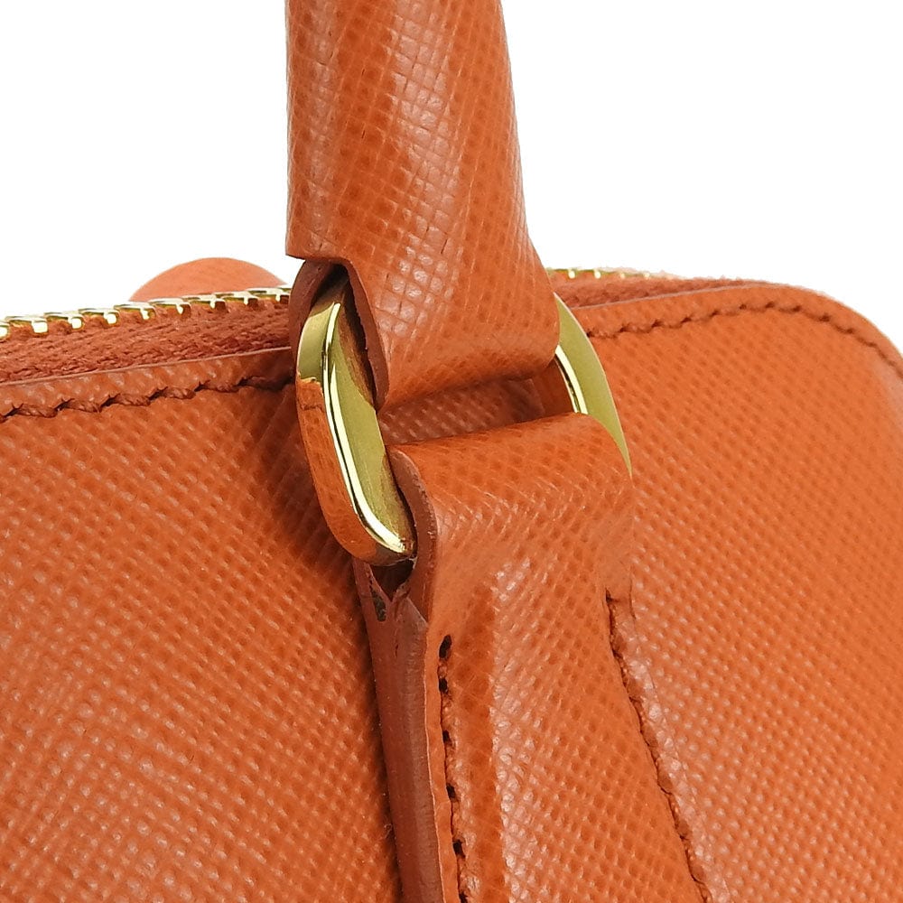 Close-up of a brown leather handbag with gold hardware on a white background