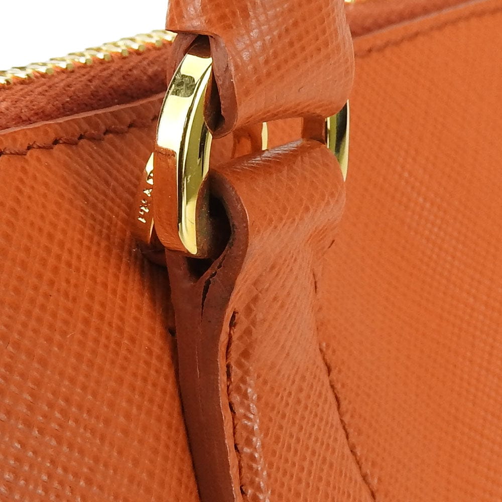 Close-up of an orange textured handbag with a gold clasp.