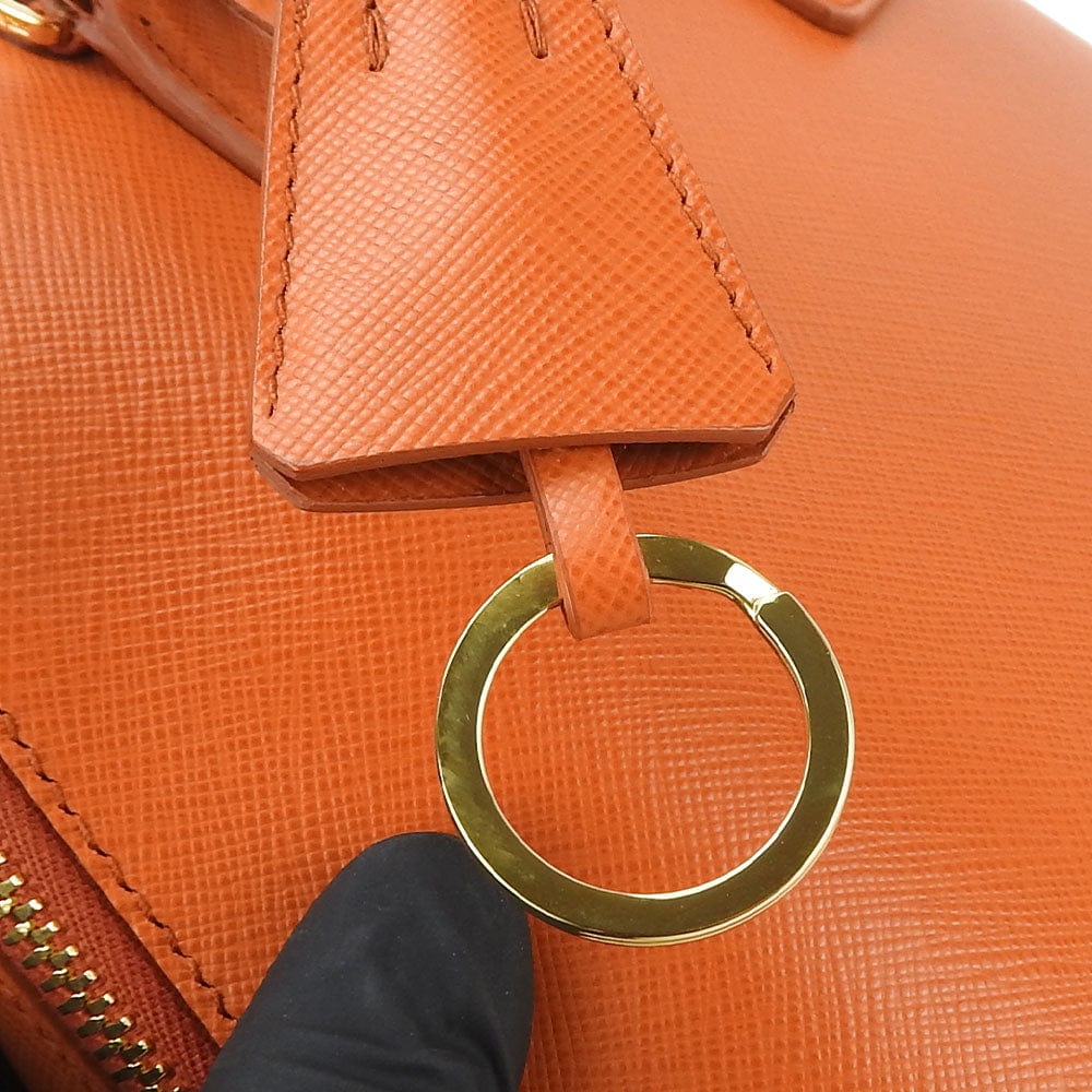 Close-up of an orange textured bag with a gold ring handle.