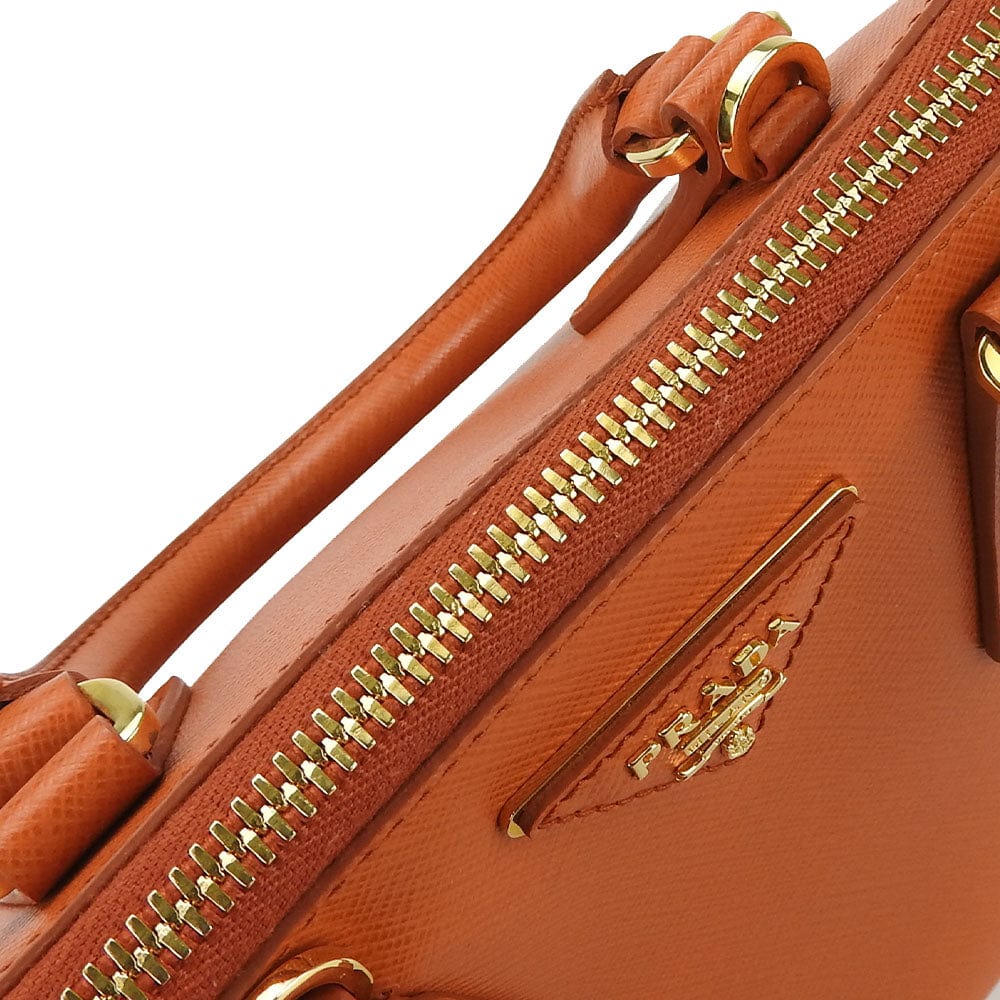 Close-up of a brown leather handbag with gold zipper and hardware.