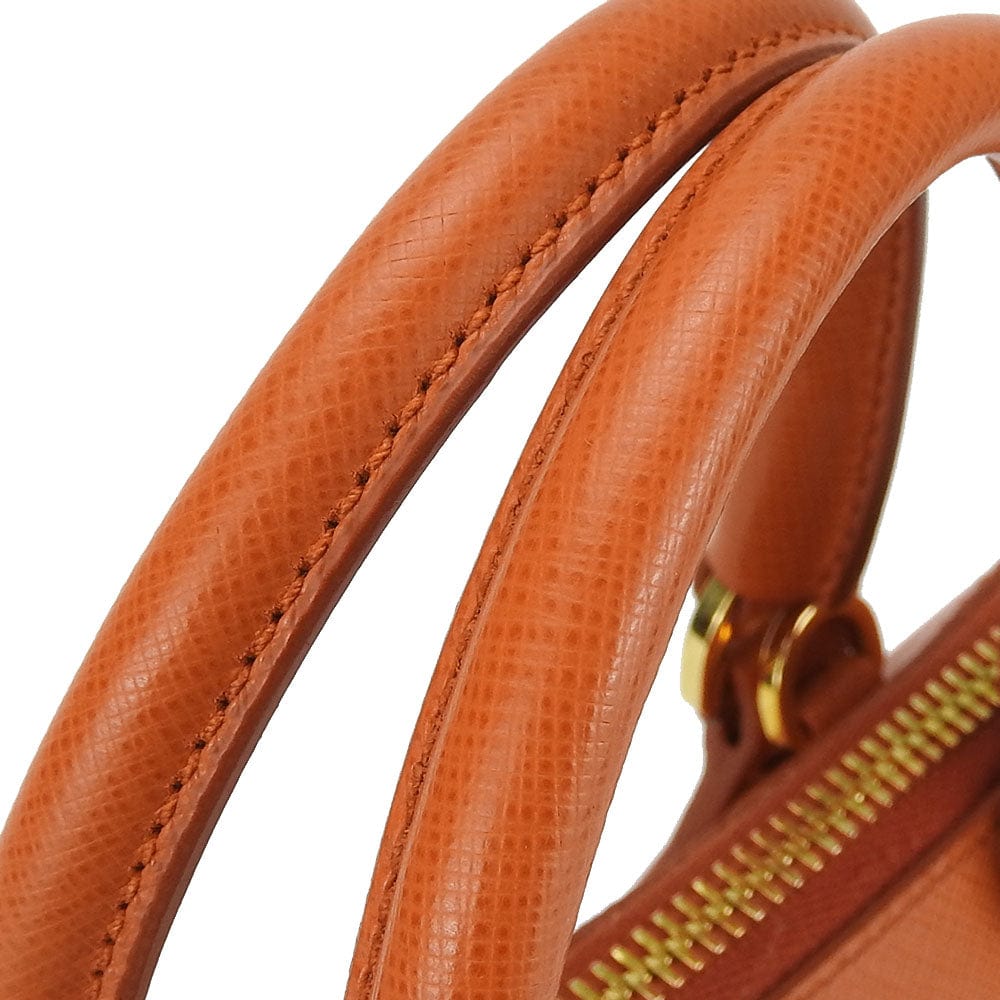 Close-up of a brown leather handbag handle with gold zipper