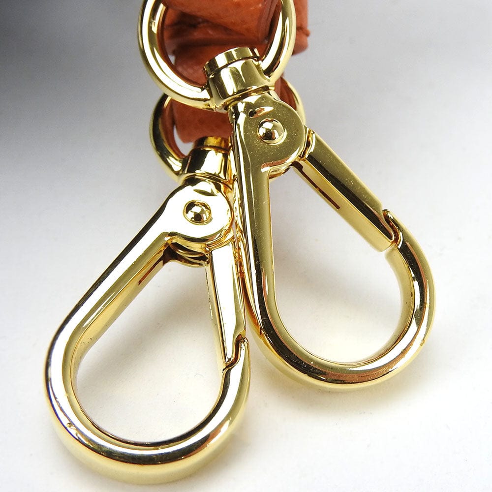 Gold metal clasp on a leather strap against a white background