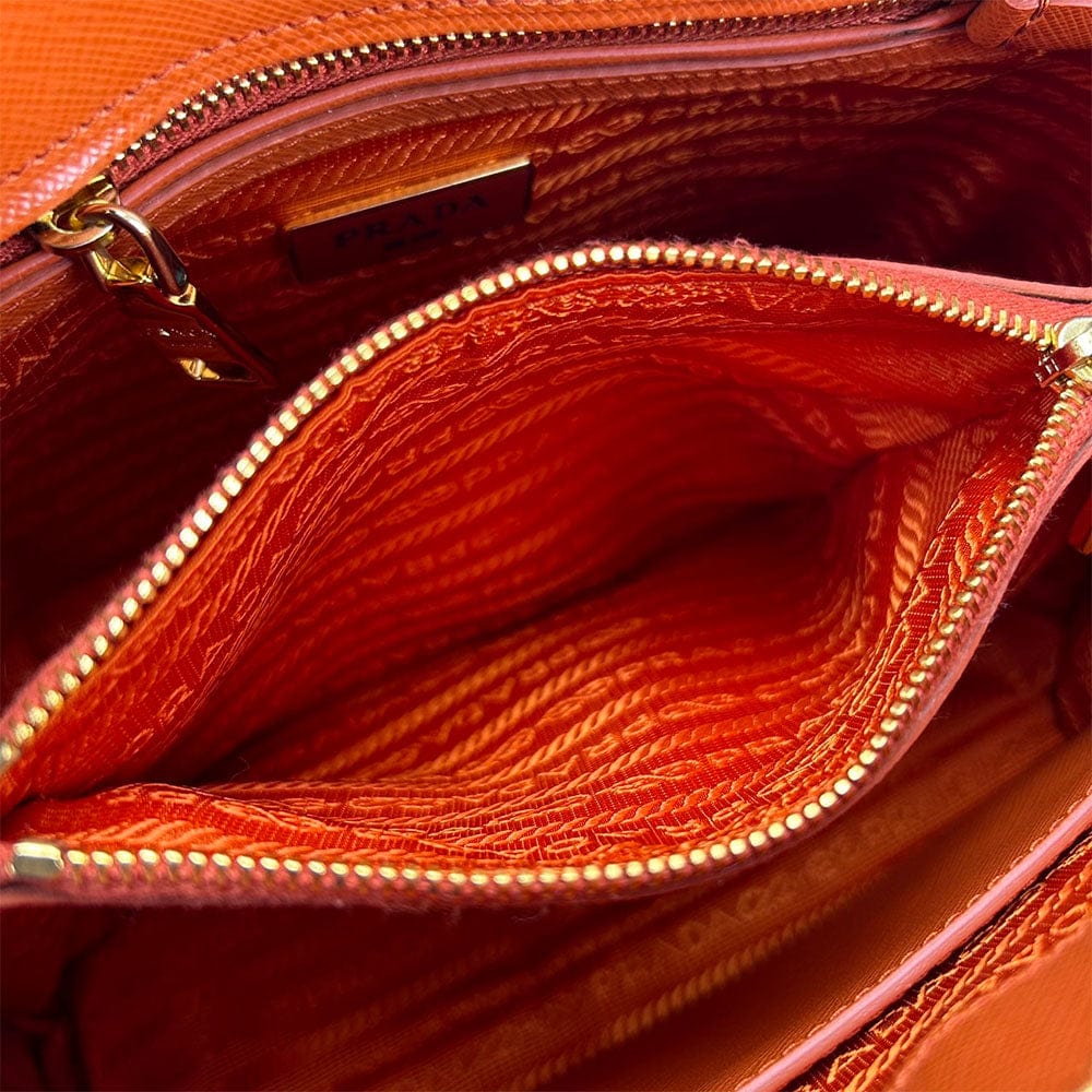 Close-up of a brown leather handbag with gold zipper and stitching detail.