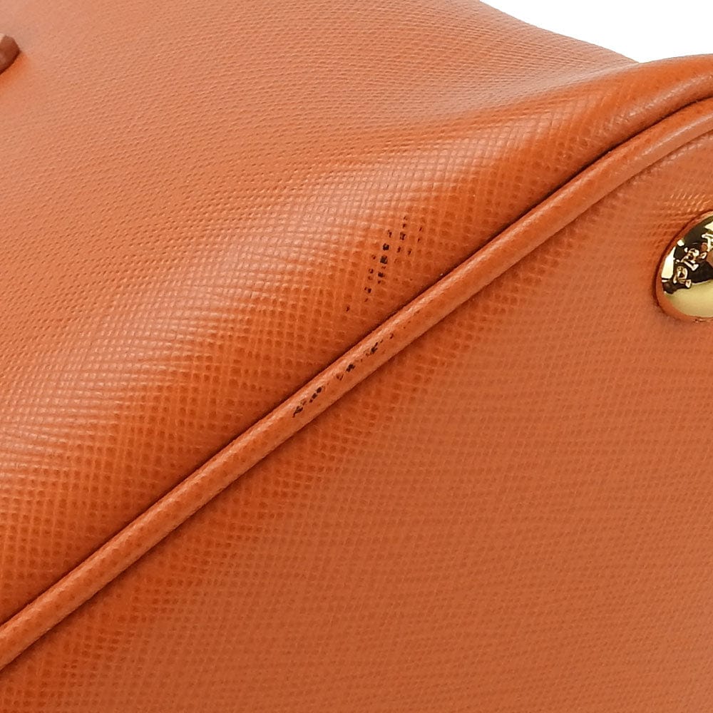 Close-up of an orange leather bag with a gold clasp.
