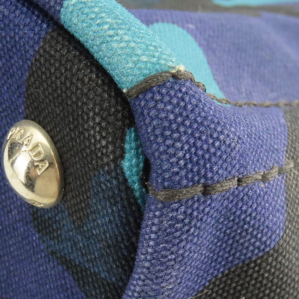 Close-up of a textured fabric surface with a gold Prada button.