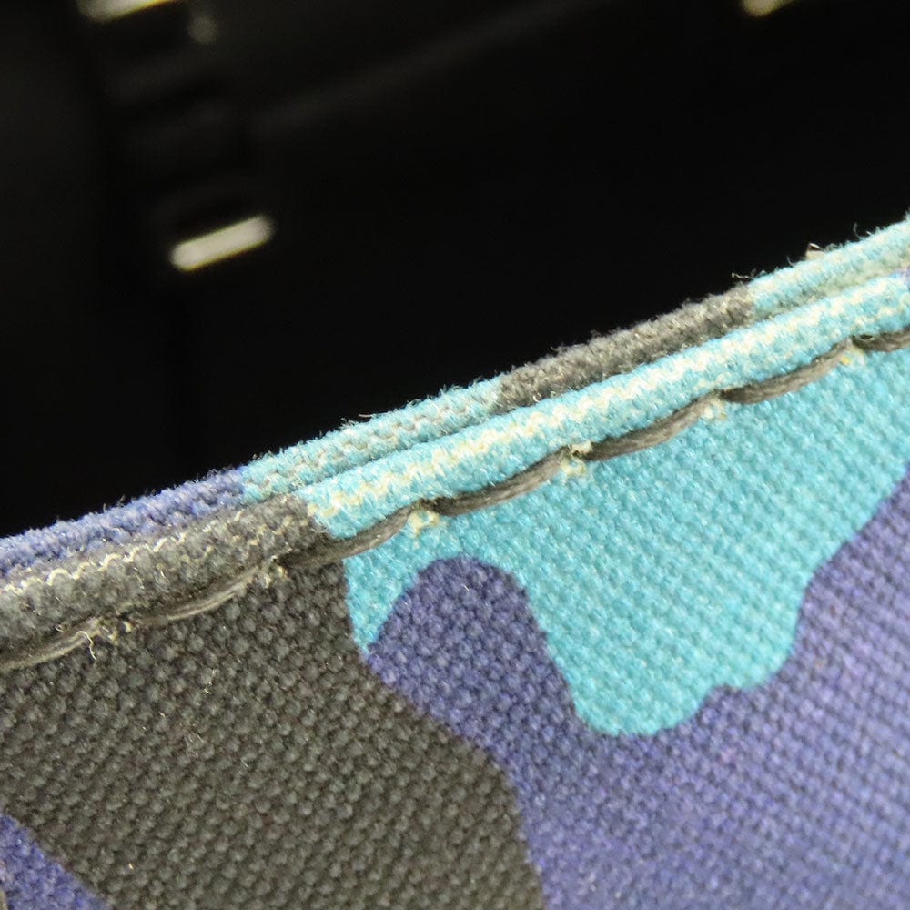 Close-up of a fabric with camouflage pattern and visible stitching.