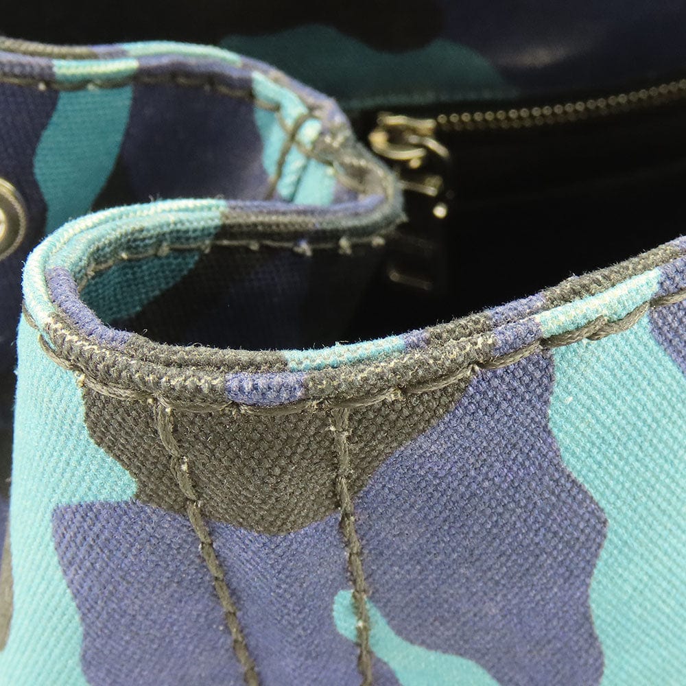 Close-up of a teal and purple camouflage-patterned bag with gold zipper.