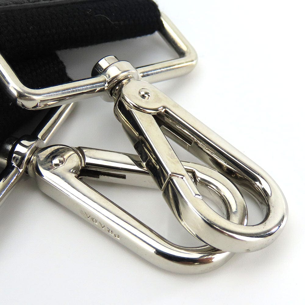 Close-up of a silver metal clip on a black strap against a white background