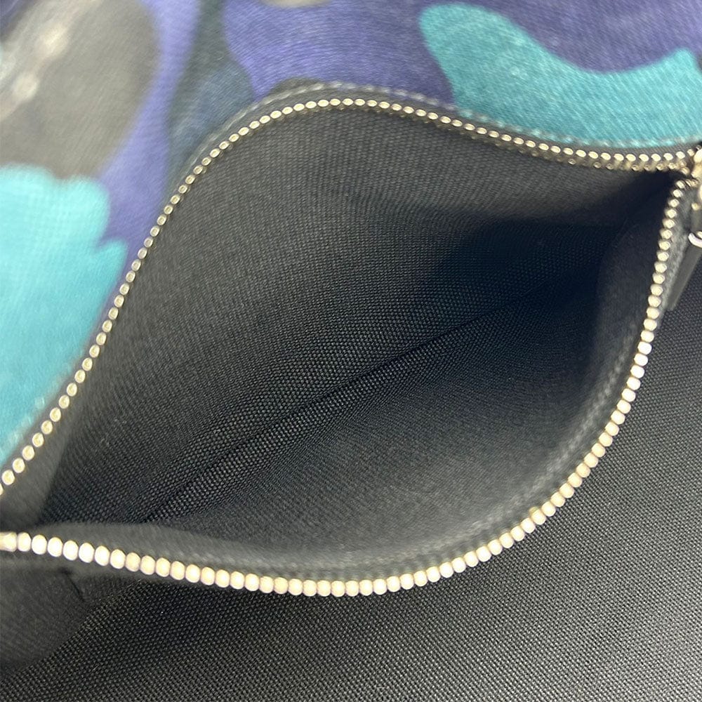 Close-up of a zipper on a black fabric surface with a colorful pattern in the background.