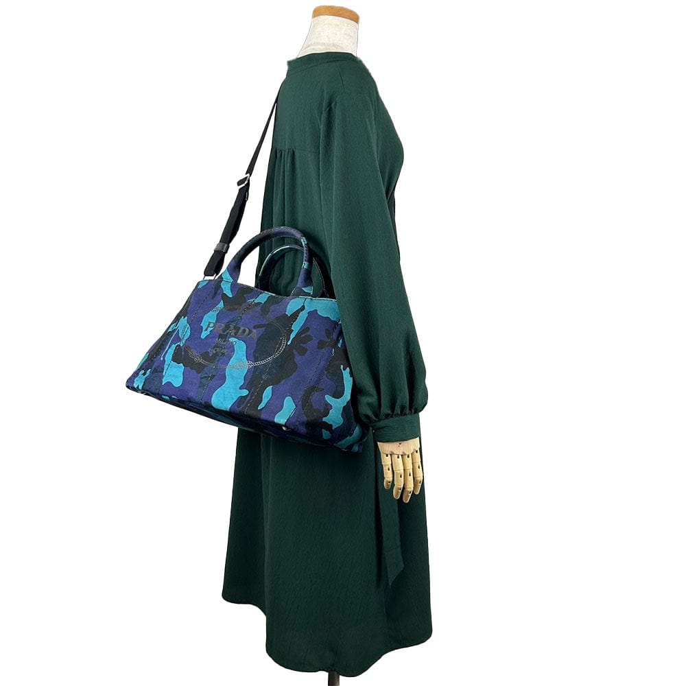 Mannequin wearing a green dress with a blue and black patterned handbag.