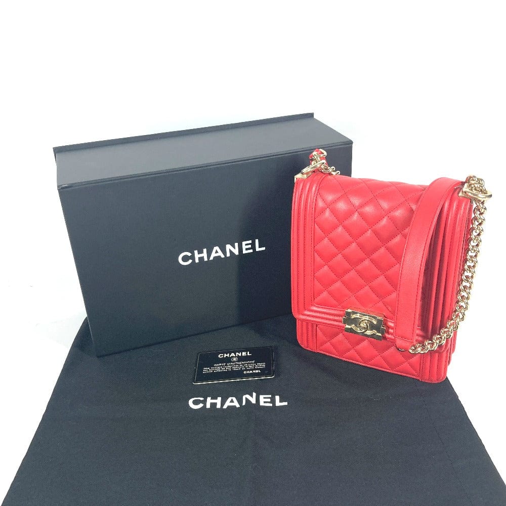 Red quilted handbag with gold chain and Chanel box on a white background