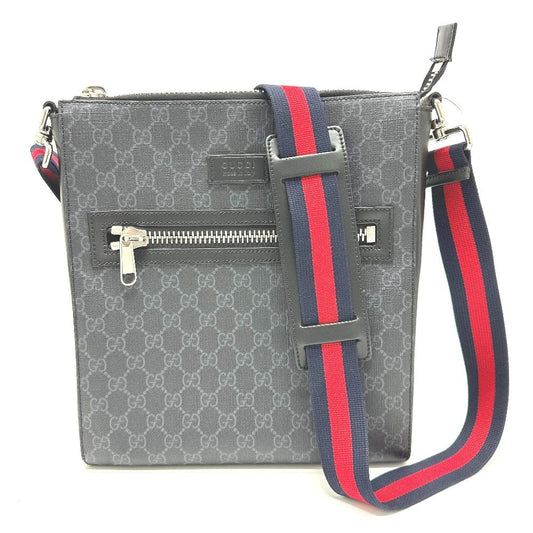 Gray patterned handbag with a red and blue strap on a white background