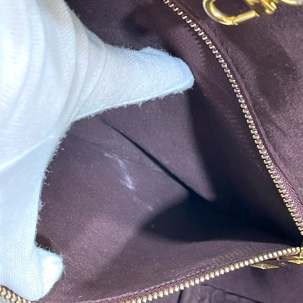 Close-up of a purple handbag with gold zipper and logo.