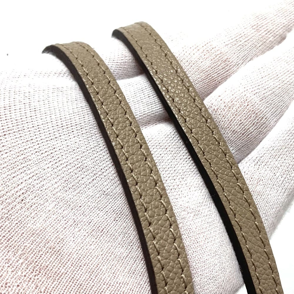 Two beige leather straps on a white fabric background