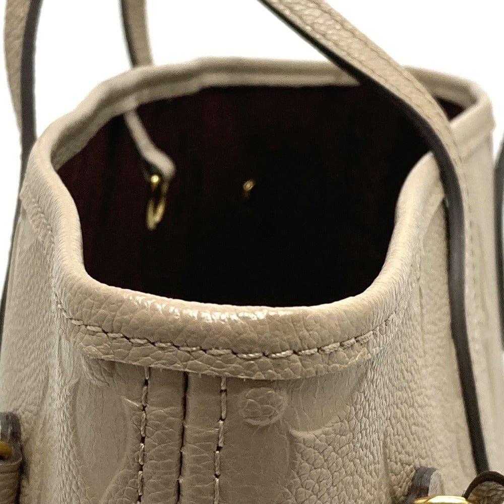 Close-up of a beige leather handbag with visible stitching and hardware.