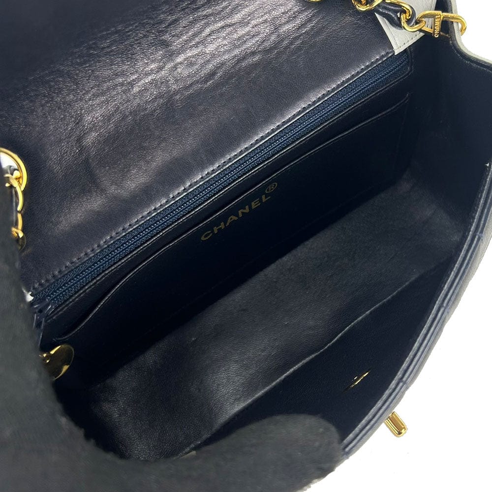 Close-up of a Chanel handbag with gold hardware on a white background