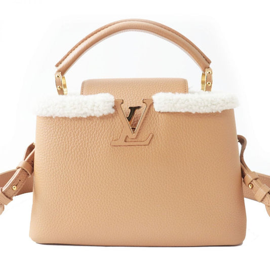 Beige handbag with white fur trim and gold hardware on a white background