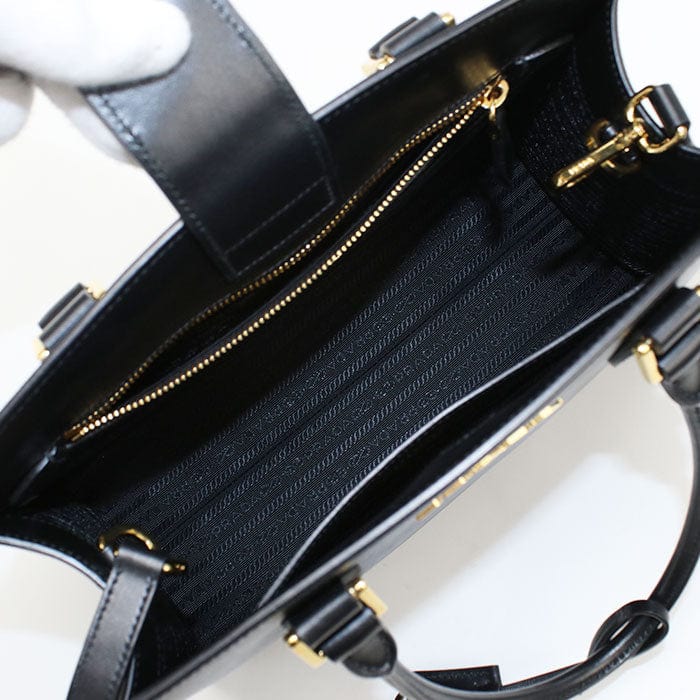 Black handbag with gold zippers on a white background