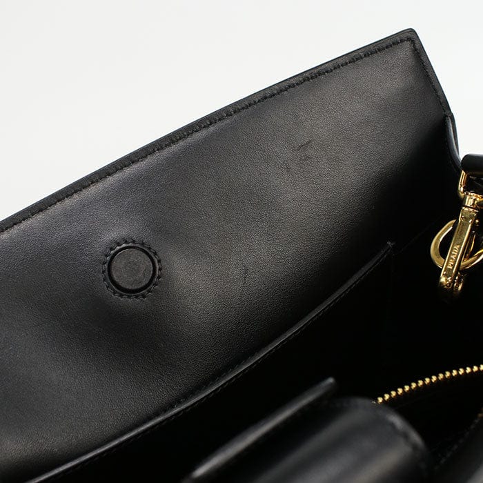 Close-up of a black leather handbag with gold zipper detail on a white background