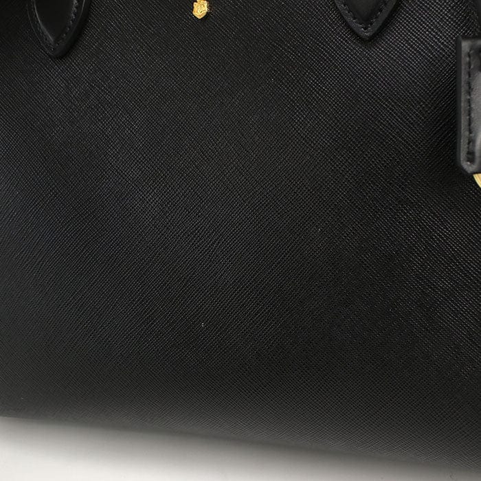 Close-up of a black textured handbag with a brand logo on a white background