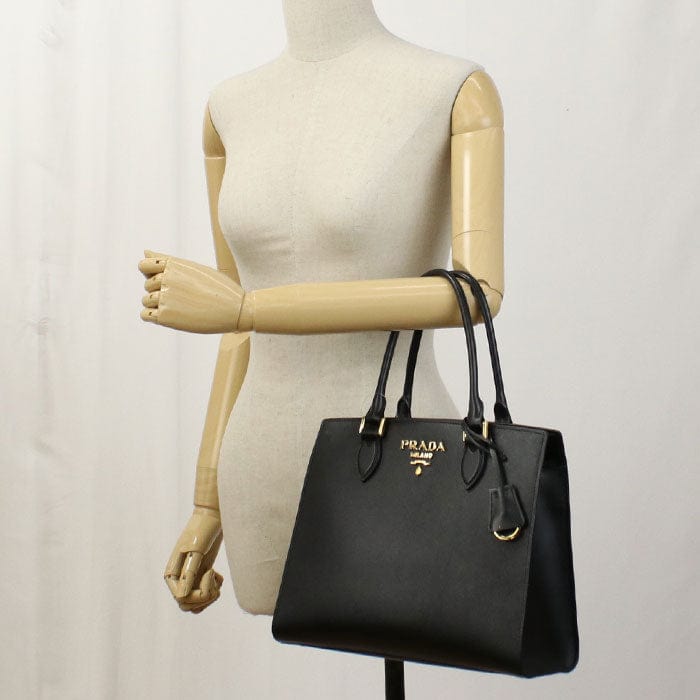 Black Prada handbag on a mannequin arm against a plain background