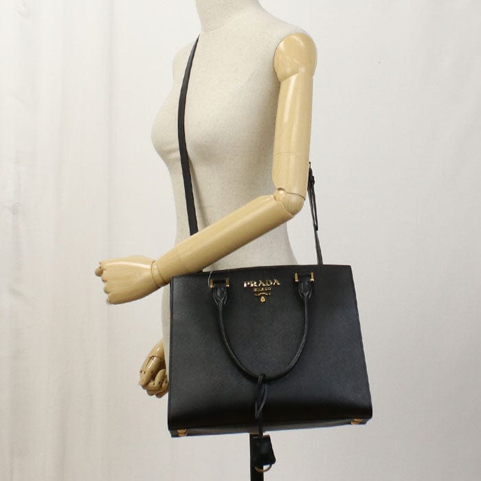 Black Prada handbag on a mannequin with a plain background