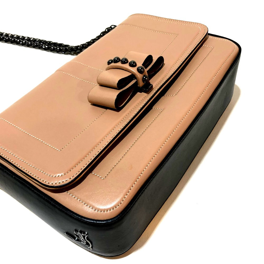 Tan and black handbag with a decorative bow on a white background