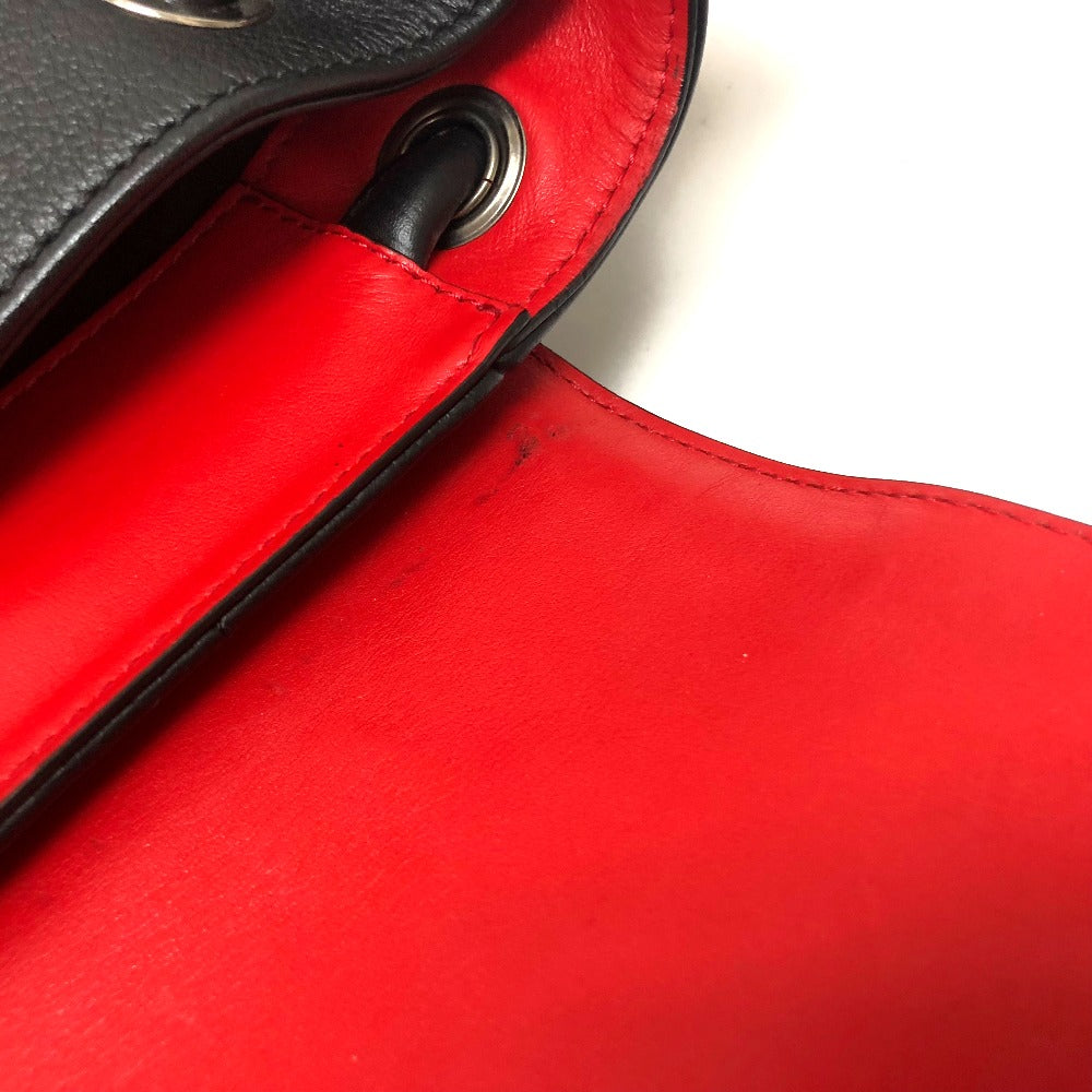 Close-up of a red leather handbag with a black strap.