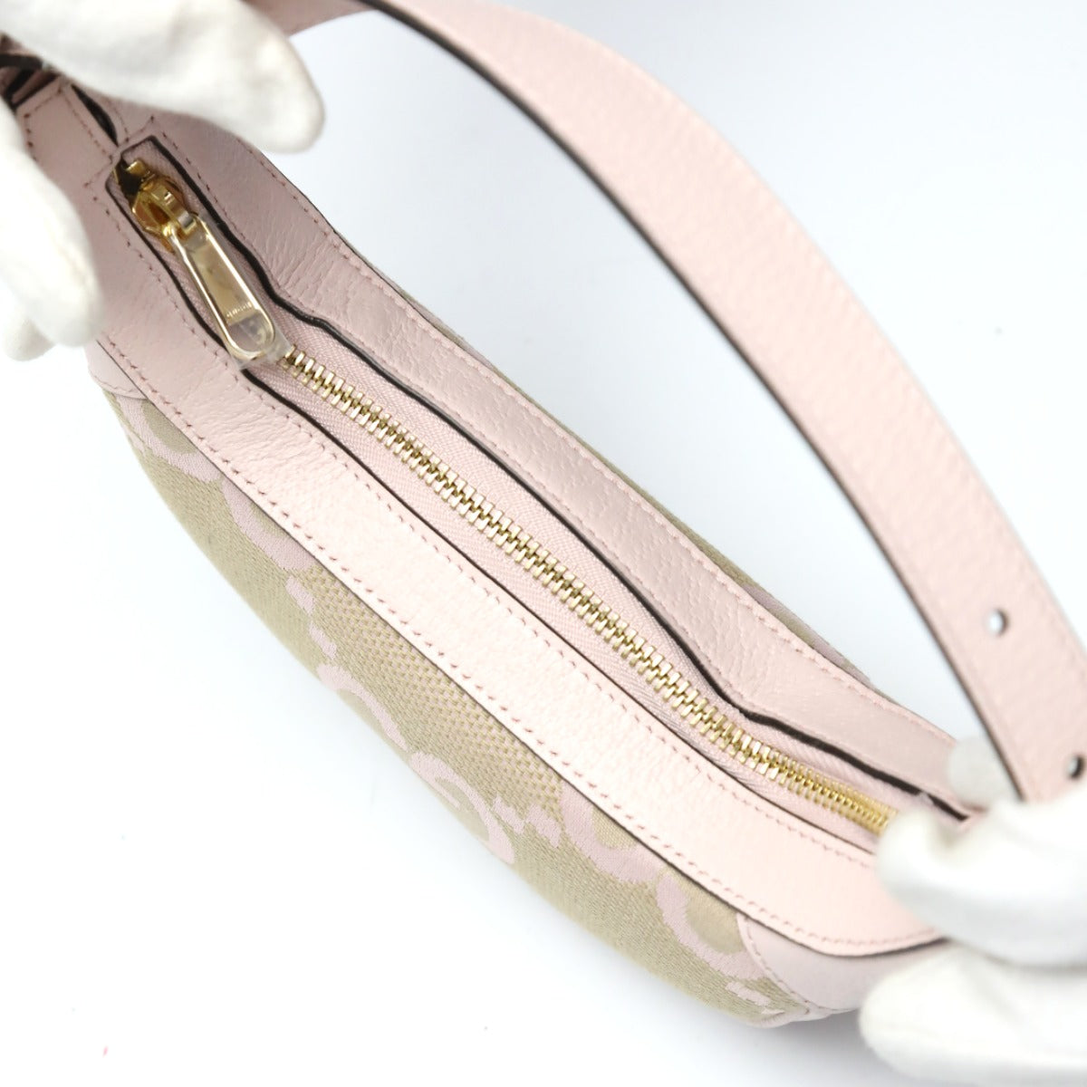 Close-up of a pink handbag with gold zipper on a white background