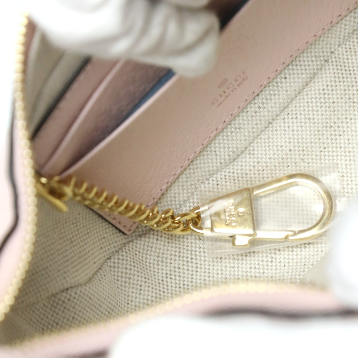 Close-up of a gold zipper on a beige fabric bag with a blurred background